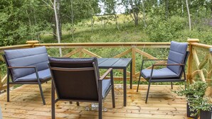 Una terraza de madera con una mesa y cuatro sillas.