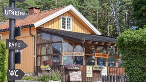 Puinen rakennus, jonka yläpuolella on kyltti, jossa lukee ”Gärdsbutikk” ja ”Gärdskaffe”. Tolpassa on lisäksi kyltit, joissa lukee ”KAFE” ja ”WC”.
