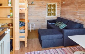 Une pièce de taille modeste, comprenant un canapé, un petit tabouret, un mur en bois et une fenêtre décorée.
