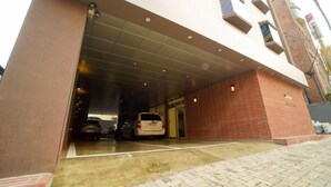 A modern building with a covered entrance, a brick facade, and a paved driveway. - Hotel Mare (Busan)