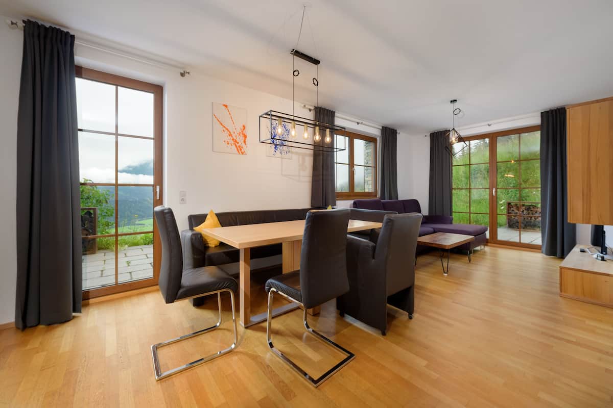 A modern dining area with a wooden table, black chairs, and a sofa.