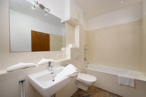 Un baño moderno con lavamanos, inodoro y bañera, todo en color blanco.