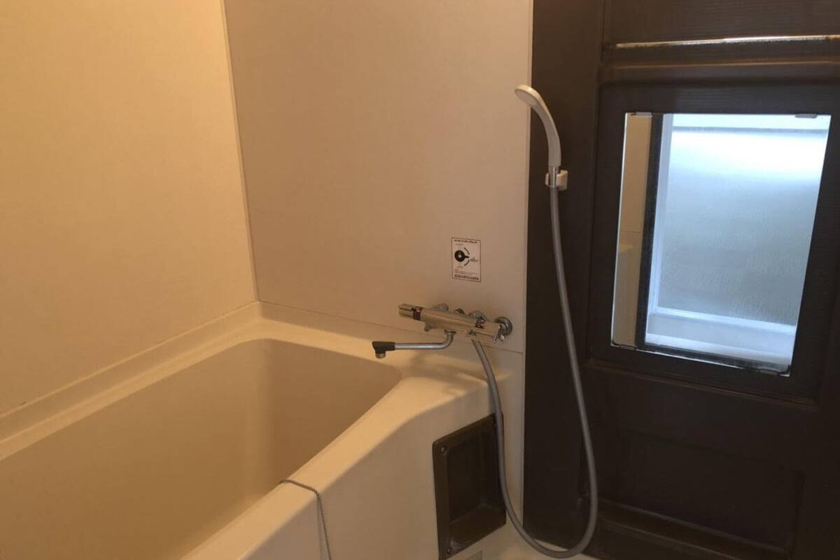 A bathroom with a bathtub, a shower, and a window.