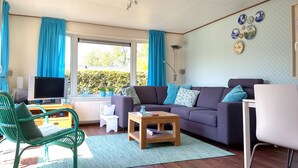 A living room with a sofa, a green chair, a small table, and a TV.