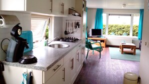 A compact kitchen with a stove, sink, and a dining area with a table and chairs.