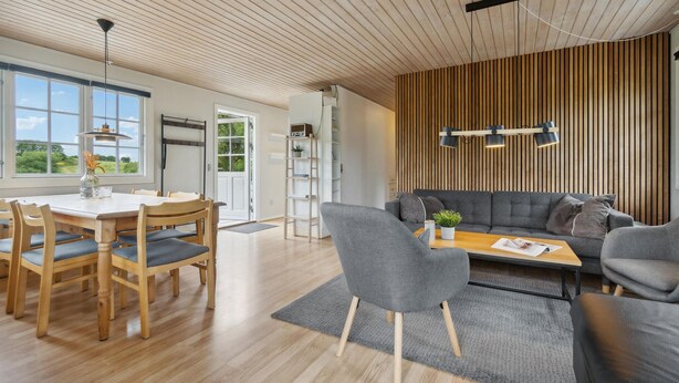 A modern living space with a dining area, a sofa set, and a wooden ceiling. - Cozy home in Tranekær with kitchen (Tranekær)