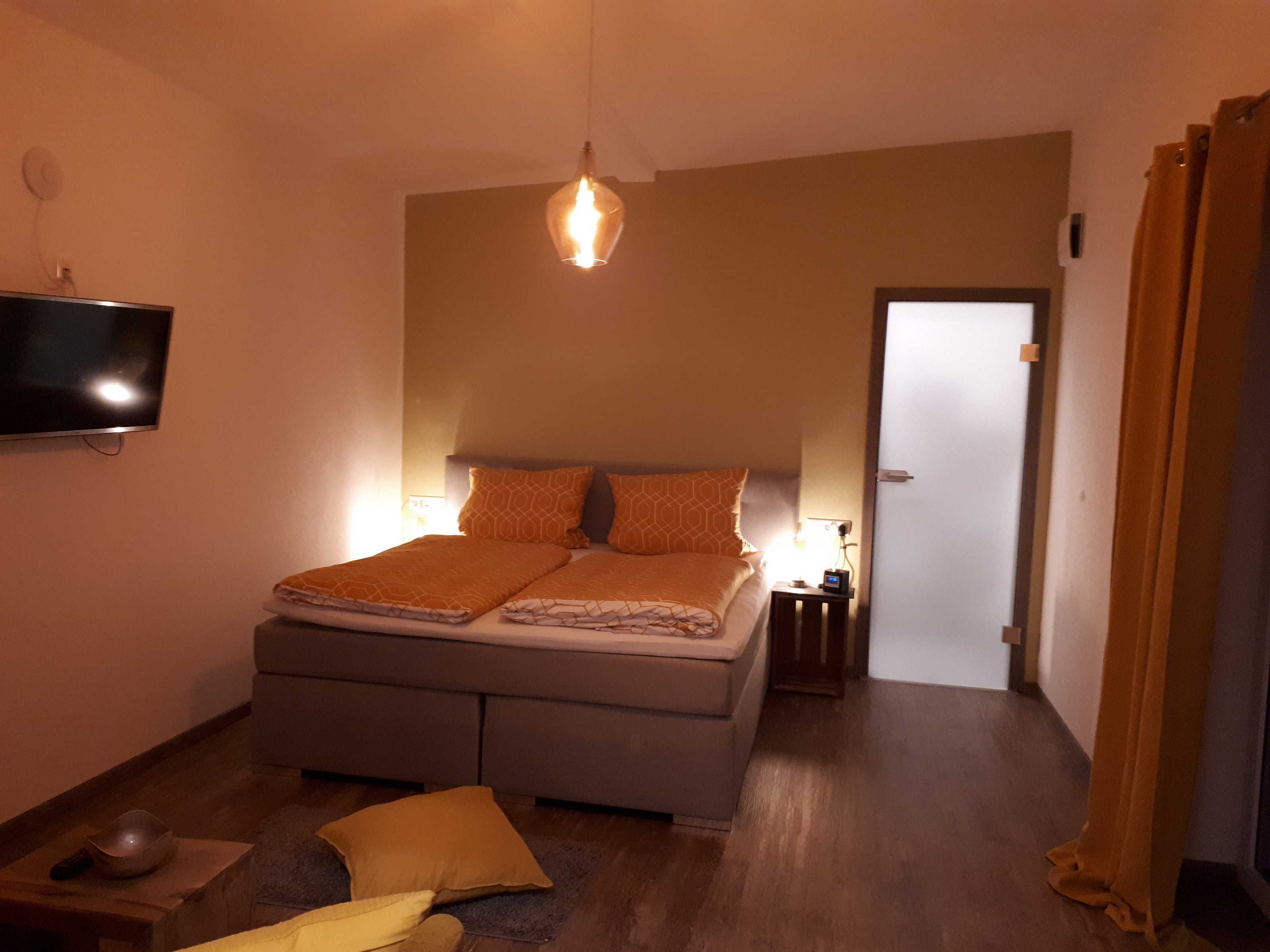 Ein Schlafzimmer mit einem Bett, Nachttischlampen, einem Fernseher und einer Tür.