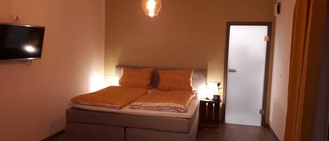 Ein Schlafzimmer mit einem Bett, Nachttischlampen, einem Fernseher und einer Tür.