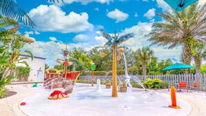 A water fountain area with a ship, palm trees, and a wooden fence.