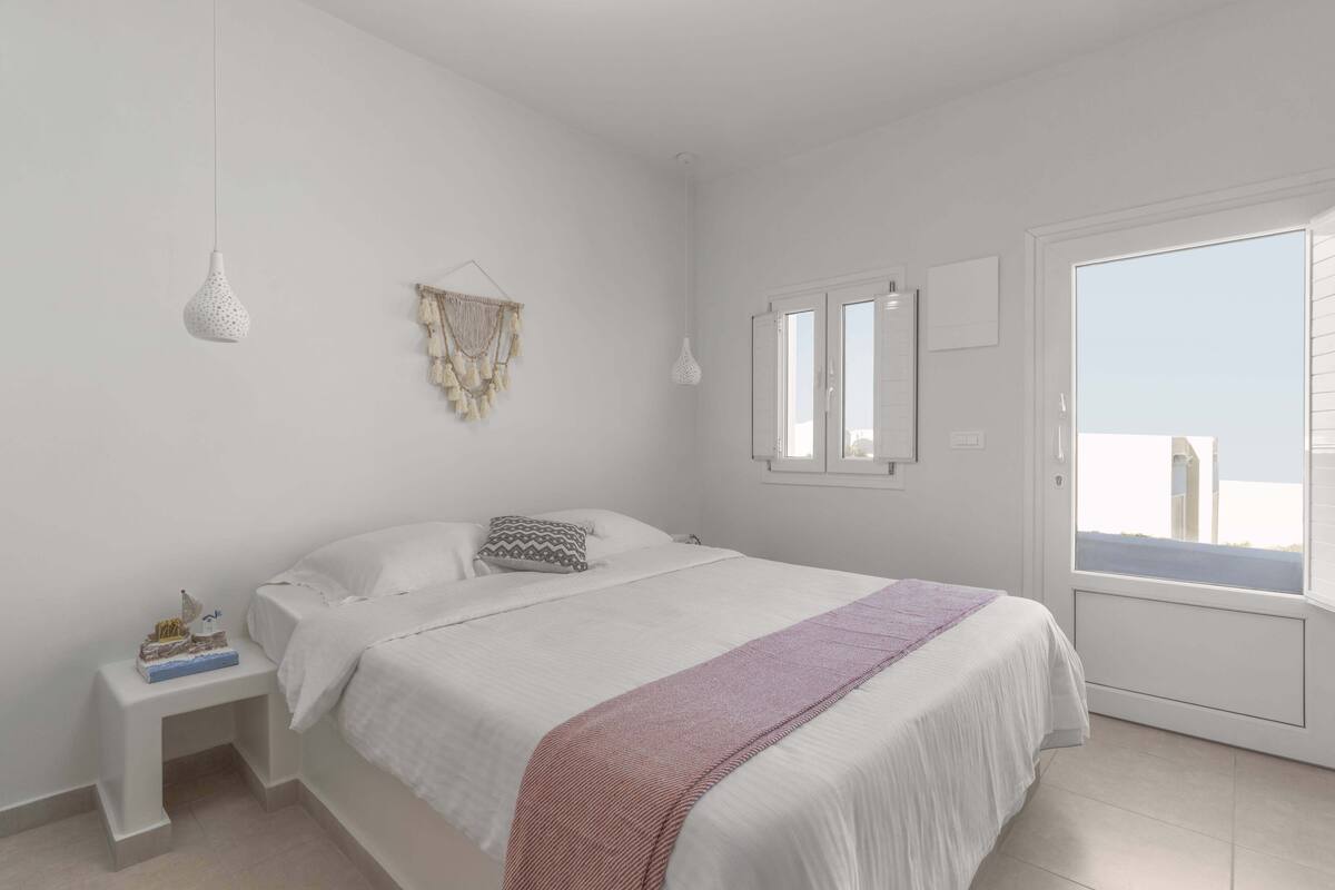 Une chambre à coucher avec un lit, une table de chevet, des éléments de décoration murale et une fenêtre.