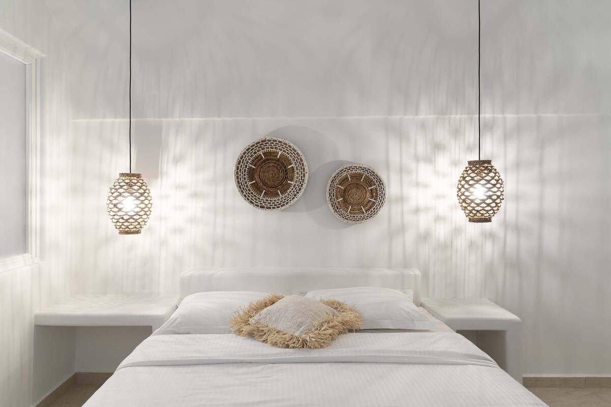 Une chambre à coucher comprenant un lit, deux tables de chevet et trois lampes fixées au mur.