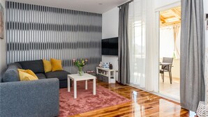 A modern living room with a grey sofa, a small white table, and a pink rug. - Stunning home in Bilice (Bilice)