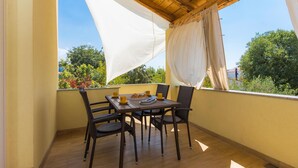 A balcony with a table and chairs, a white canopy, and a view of greenery and buildings. - Stunning home in Bilice (Bilice)