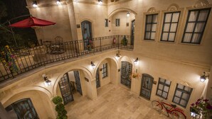 A multi-level courtyard with a red bicycle, potted plants, and a red umbrella. - Sinasos Star Hotel Cappadocia (Ürgüp)