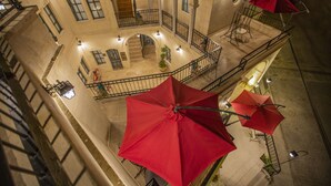 A courtyard with red umbrellas, stone walls, and a staircase. - Sinasos Star Hotel Cappadocia (Ürgüp)