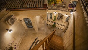 A multi-level building with a wooden staircase, stone arches, and a tiled roof. - Sinasos Star Hotel Cappadocia (Ürgüp)