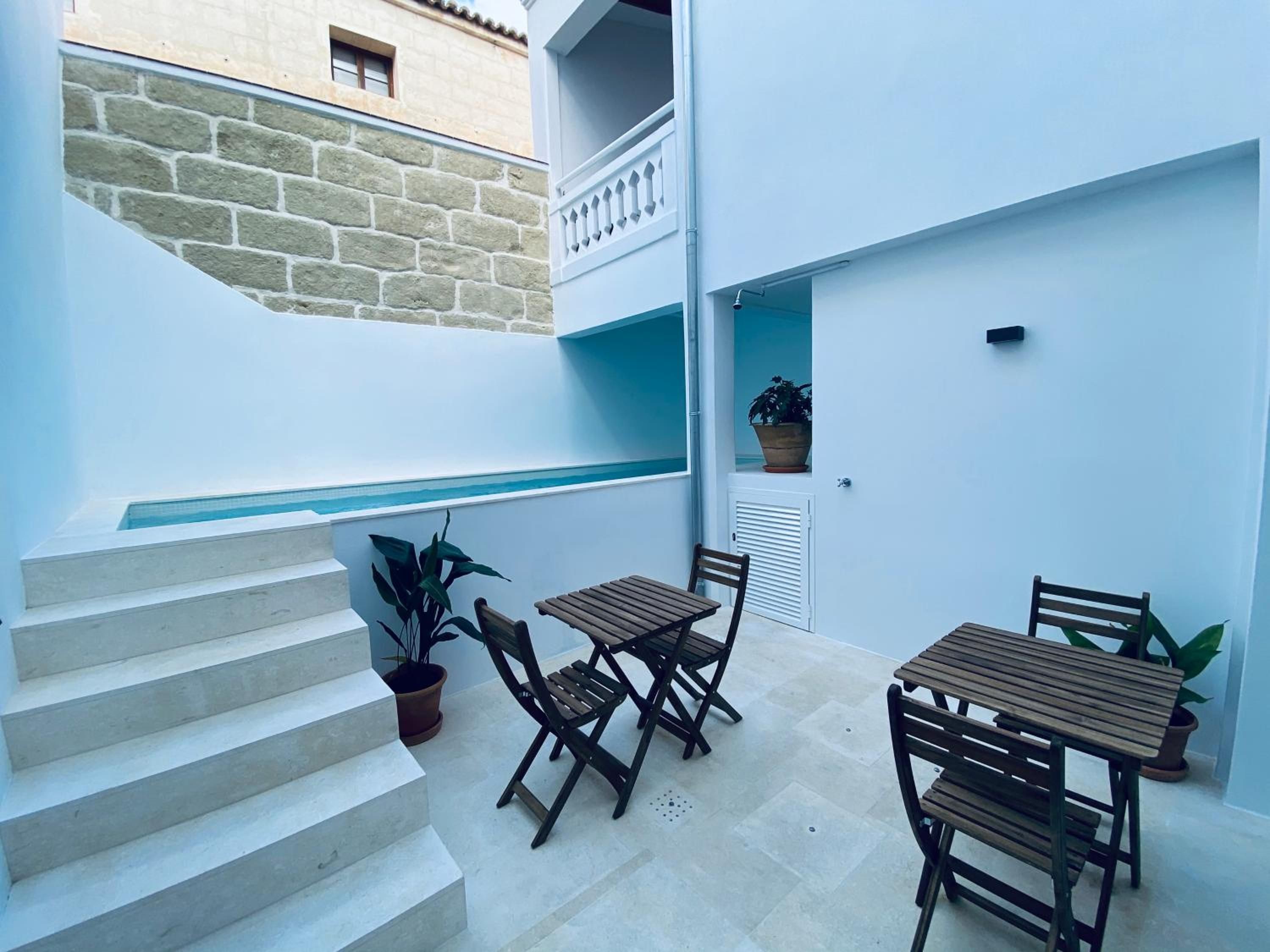 A patio area with a set of concrete stairs, a wooden table with chairs, and potted plants.