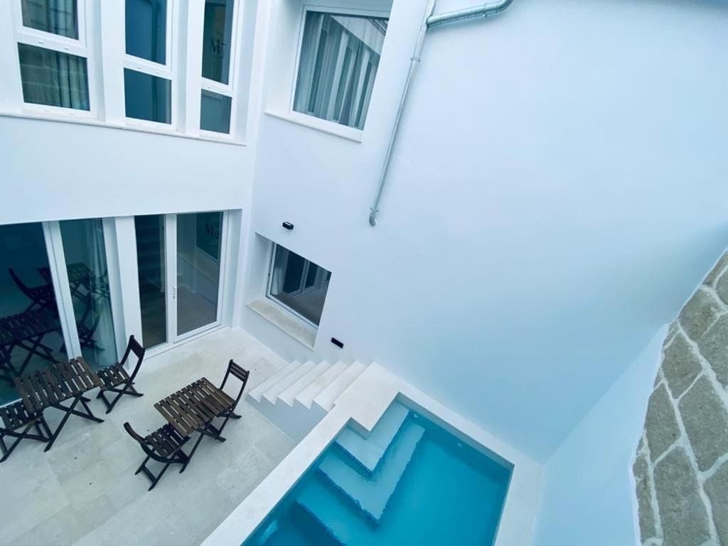 Un edificio moderno con piscina, asientos al aire libre y una escalera.