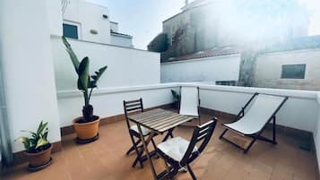 Una terraza con mesa y sillas, plantas en macetas y vistas a edificios.