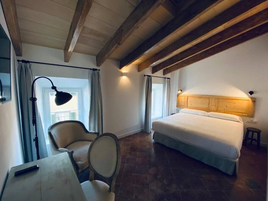 A bedroom with a bed, a chair, a desk, and a lamp.