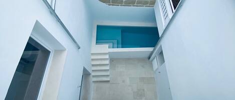 A narrow, enclosed stairwell with a blue accent wall and a stone facade.