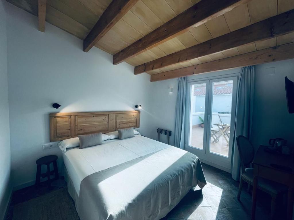 A bedroom with a large bed, wooden headboard, and a view of the outdoors through a sliding door.