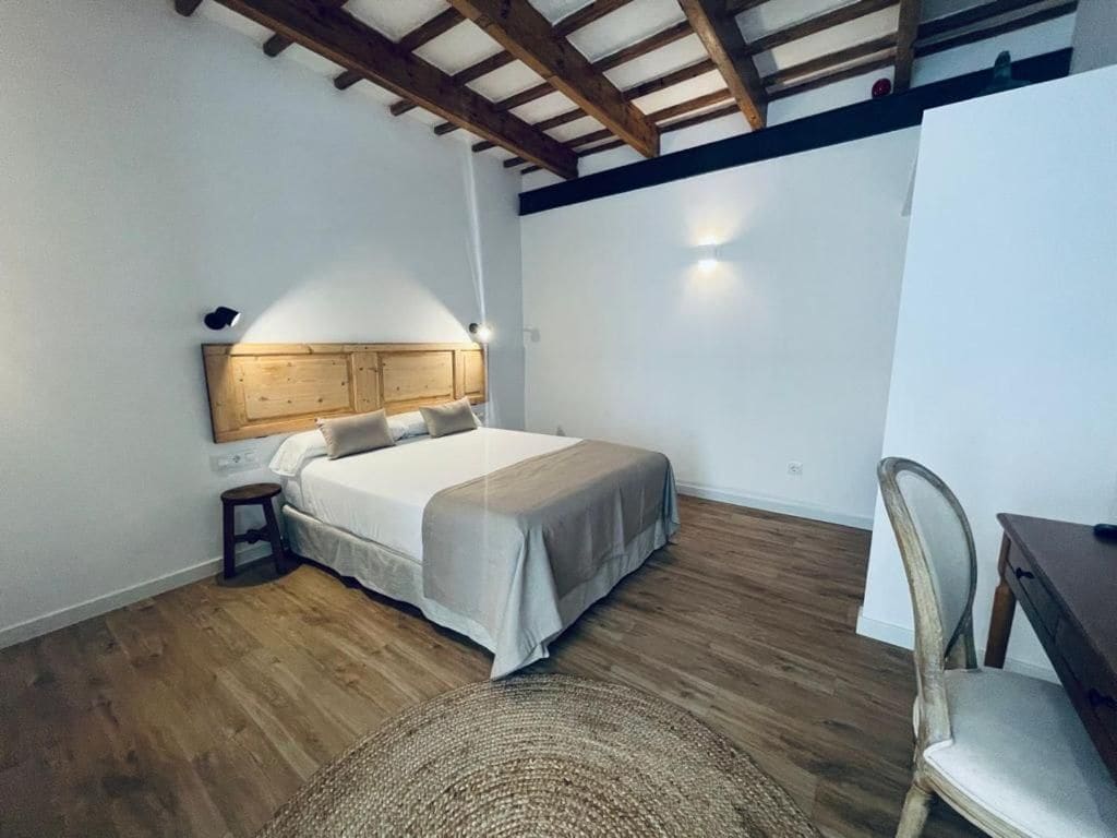 Un dormitorio con cama, mesita de noche, silla y escritorio.