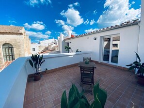 A rooftop terrace with a tiled floor, a wooden table, and potted plants. - Hotel Casa Miranda - Adults Only (Mahón)
