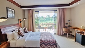 A hotel room with a bed, bedside tables, a desk, a chair, and a balcony with a view. - Kampala Nile Resort (Seeta)