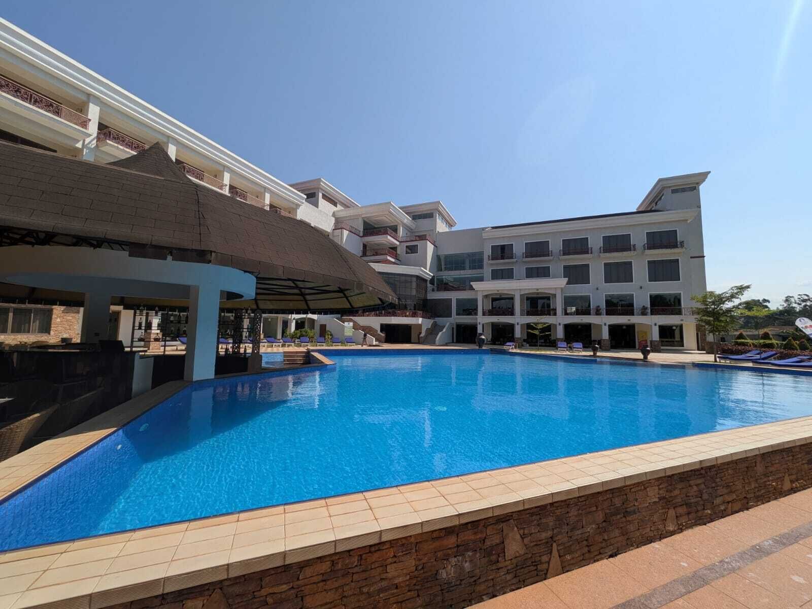 A hotel with a swimming pool, multiple balconies, and a covered area with lounge chairs.