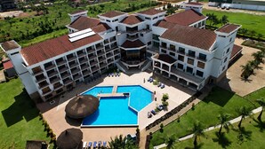 A large hotel with multiple floors, a central swimming pool, and a well-maintained lawn. - Kampala Nile Resort (Seeta)
