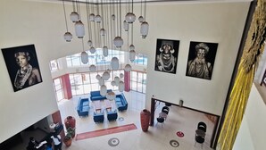 A spacious lobby with a high ceiling, hanging pendant lights, and a seating area with sofas and tables. - Kampala Nile Resort (Seeta)