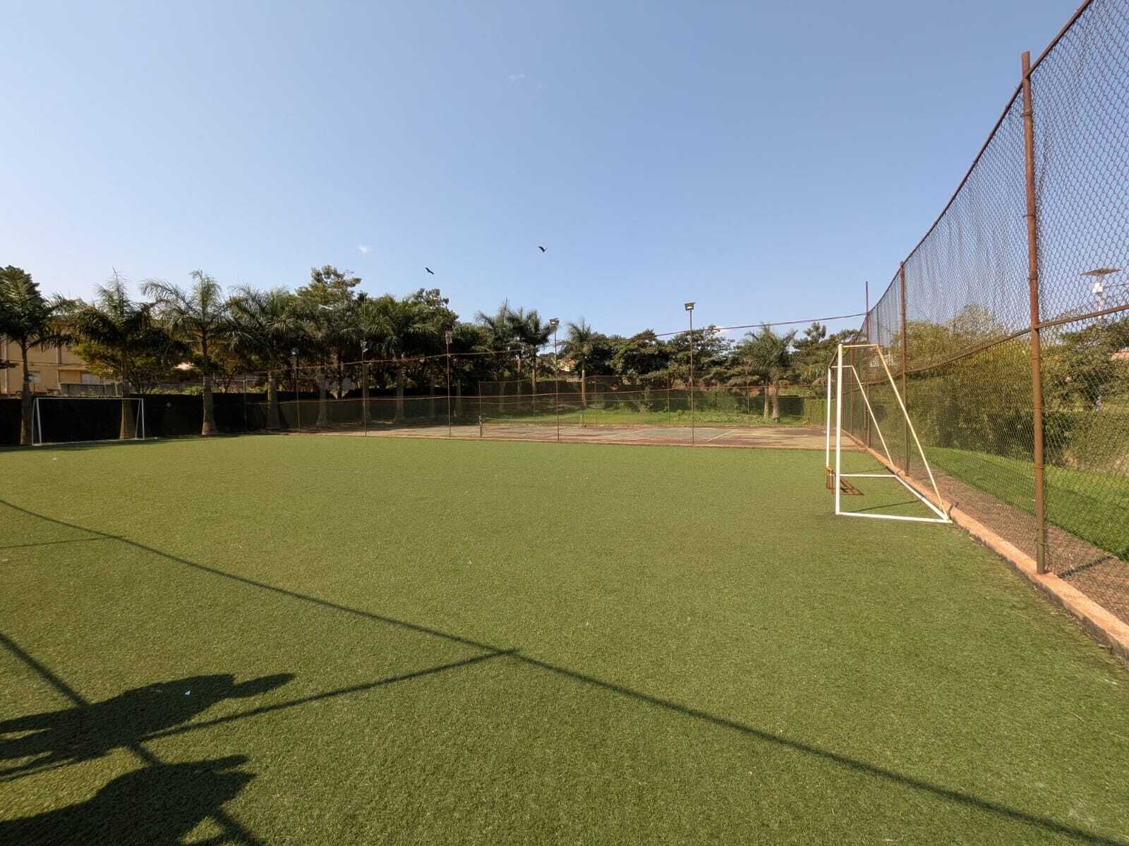 Un campo deportivo con un arco, rodeado por una cerca de alambre y árboles.