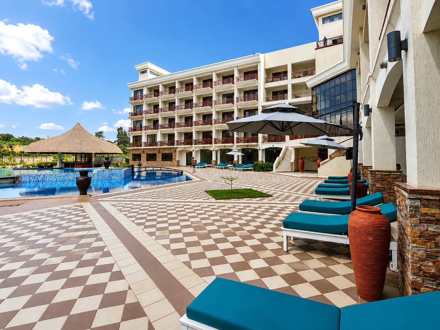 Um hotel com piscina, área de estar ao ar livre e um edifício com várias varandas.