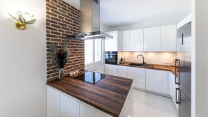 Una cucina moderna con una parete decorata in mattoni, mobili bianchi e un piano di lavoro in legno.