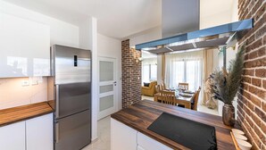 Una cucina moderna con frigorifero in acciaio inox, un piano di lavoro in legno e una parete decorata con mattoni.