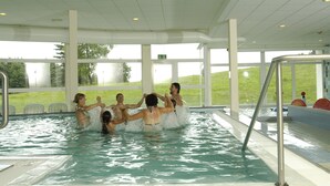 A swimming pool with clear water, surrounded by white walls and large windows. - Allgäuhaus Wertach (Wertach)