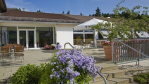 A building with a tiled roof, a covered outdoor seating area, and a staircase leading to a second floor. - Allgäuhaus Wertach (Wertach)