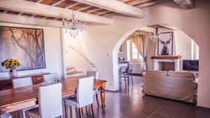 A spacious living area with a wooden dining table, white chairs, a beige sofa, and a fireplace. - House with private pool, air conditioning and stunning views!!! (Montecchio)