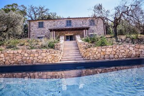 A stone house with a pool in front, surrounded by trees and a stone wall. - House with private pool, air conditioning and stunning views!!! (Montecchio)