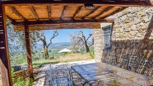 A covered outdoor seating area with a stone wall and a view of the countryside. - House with private pool, air conditioning and stunning views!!! (Montecchio)