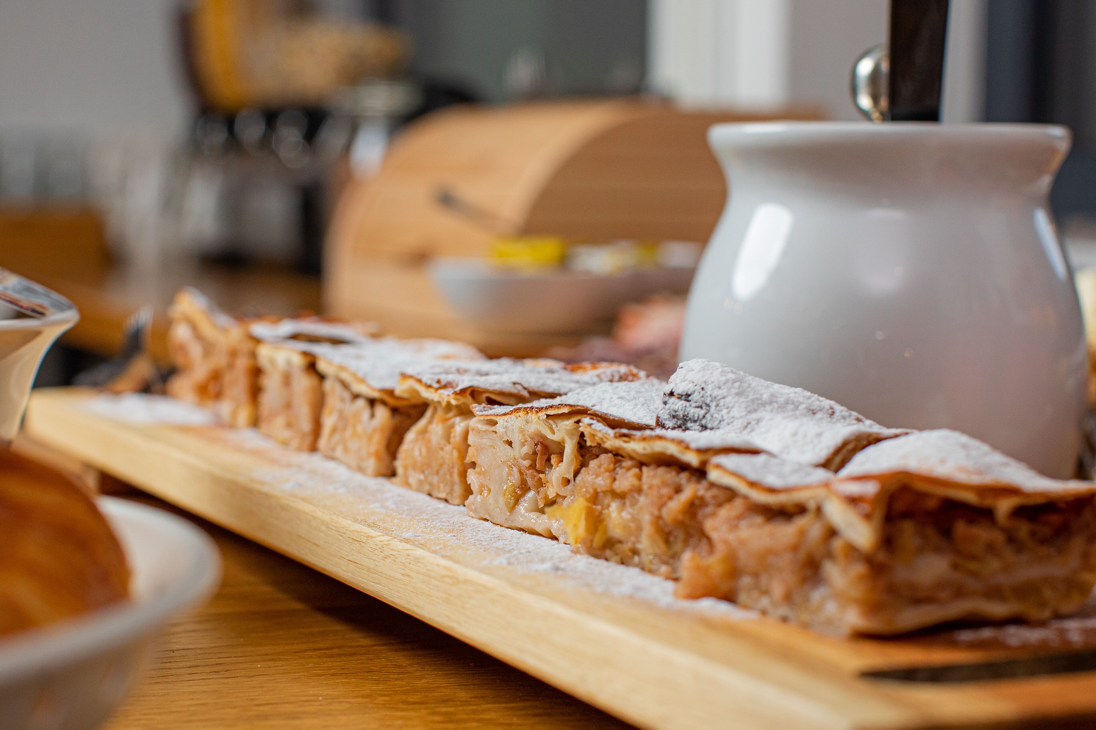 Un dessert saupoudré de sucre glace, présenté sur une planche en bois.