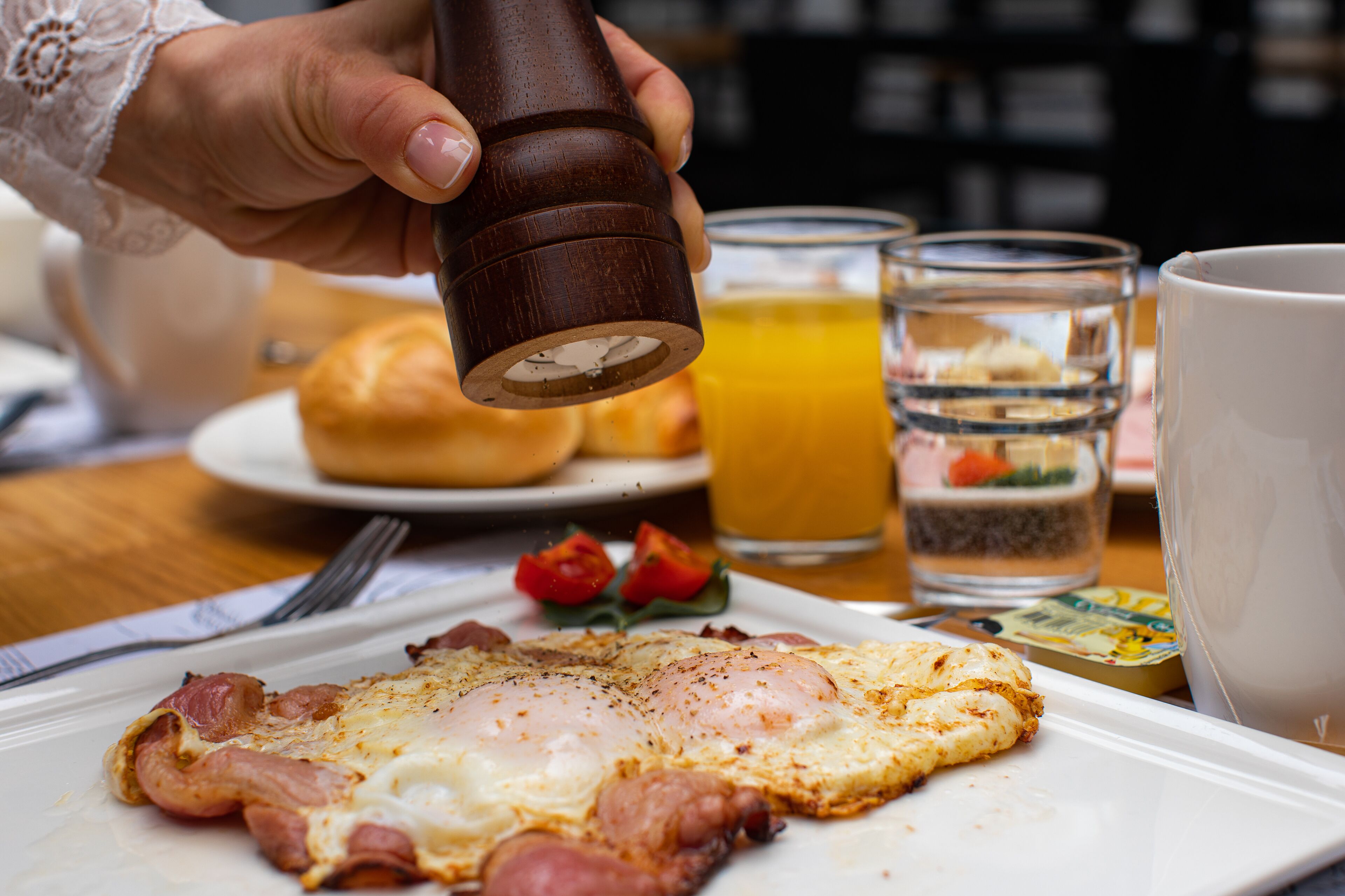 Ein Frühstückstisch mit Eiern, Toast und Tomaten, einem Glas Orangensaft und einem Salzstreuer.