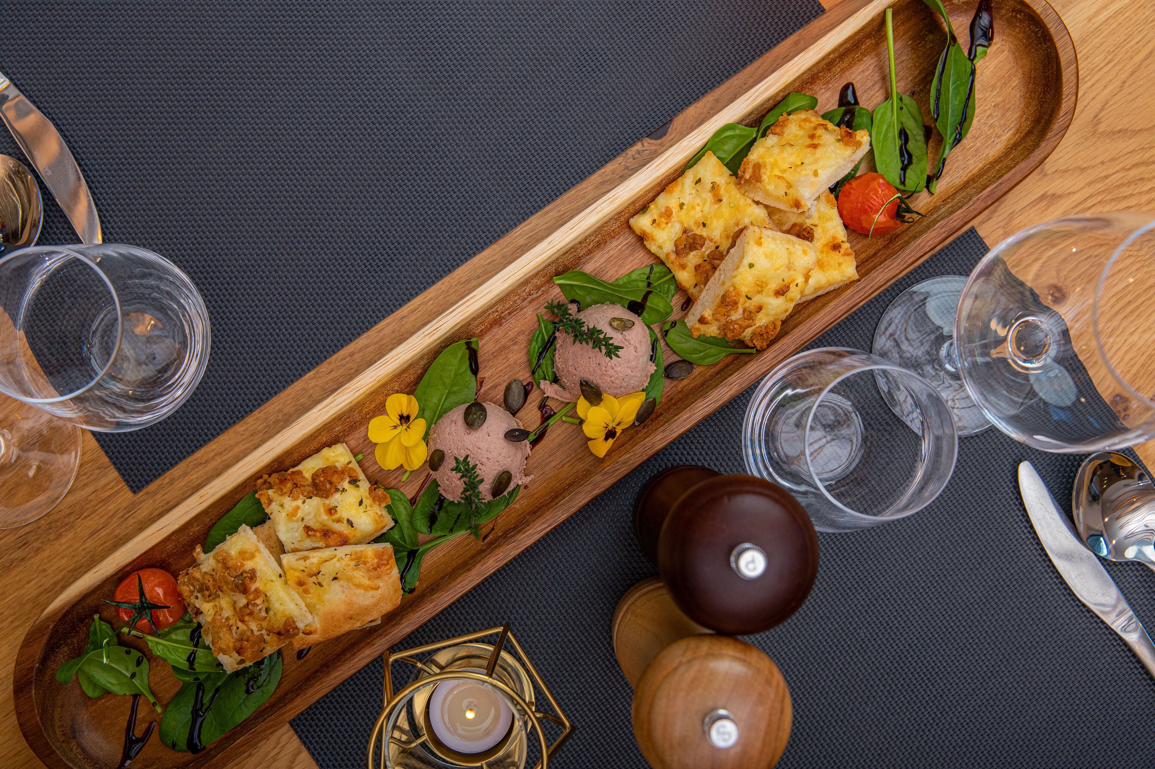 Una bandeja de madera con comida y bebidas sobre una mesa.