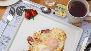 A breakfast plate with eggs, ham, and croissants, a glass of orange juice, and a cup of coffee on a wooden table.