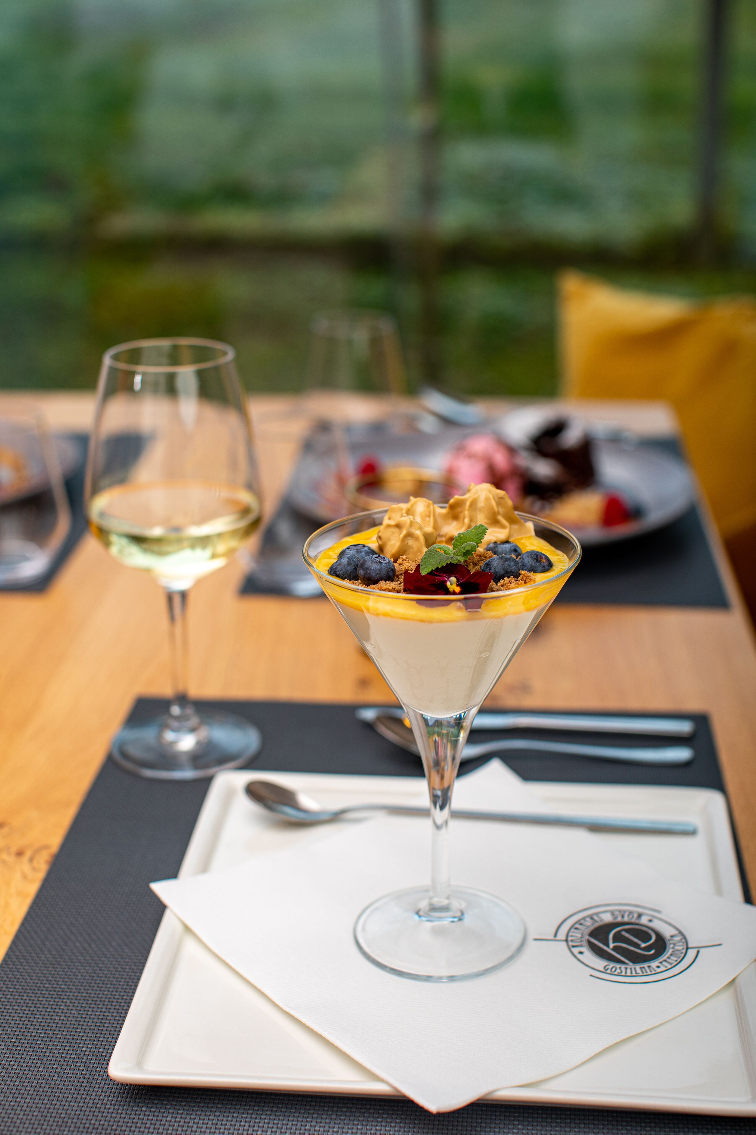 Un postre en una copa tipo martini sobre una mesa con un mantel blanco y una cuchara al lado.