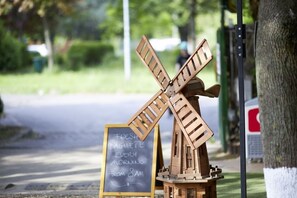 A wooden windmill model with a sign that reads "Fresh baguette every morning from 8 AM."