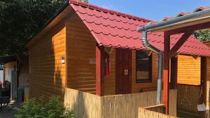 A wooden cabin with a red roof, a wooden fence, and a small window. - Haller Wooden Houses - Campsite (Budapest)