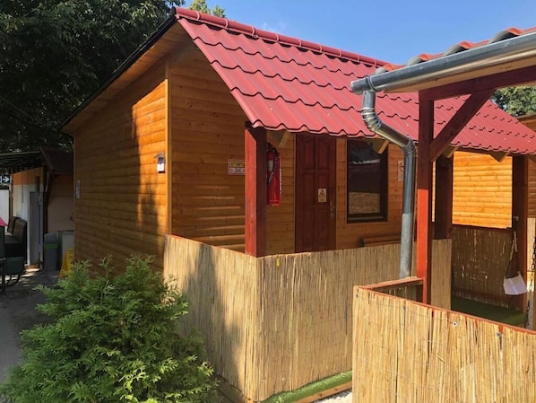 A wooden cabin with a red roof, a wooden fence, and a small window.