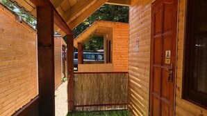 A wooden cabin with a covered porch, a wooden door, and a small window. - Haller Wooden Houses - Campsite (Budapest)